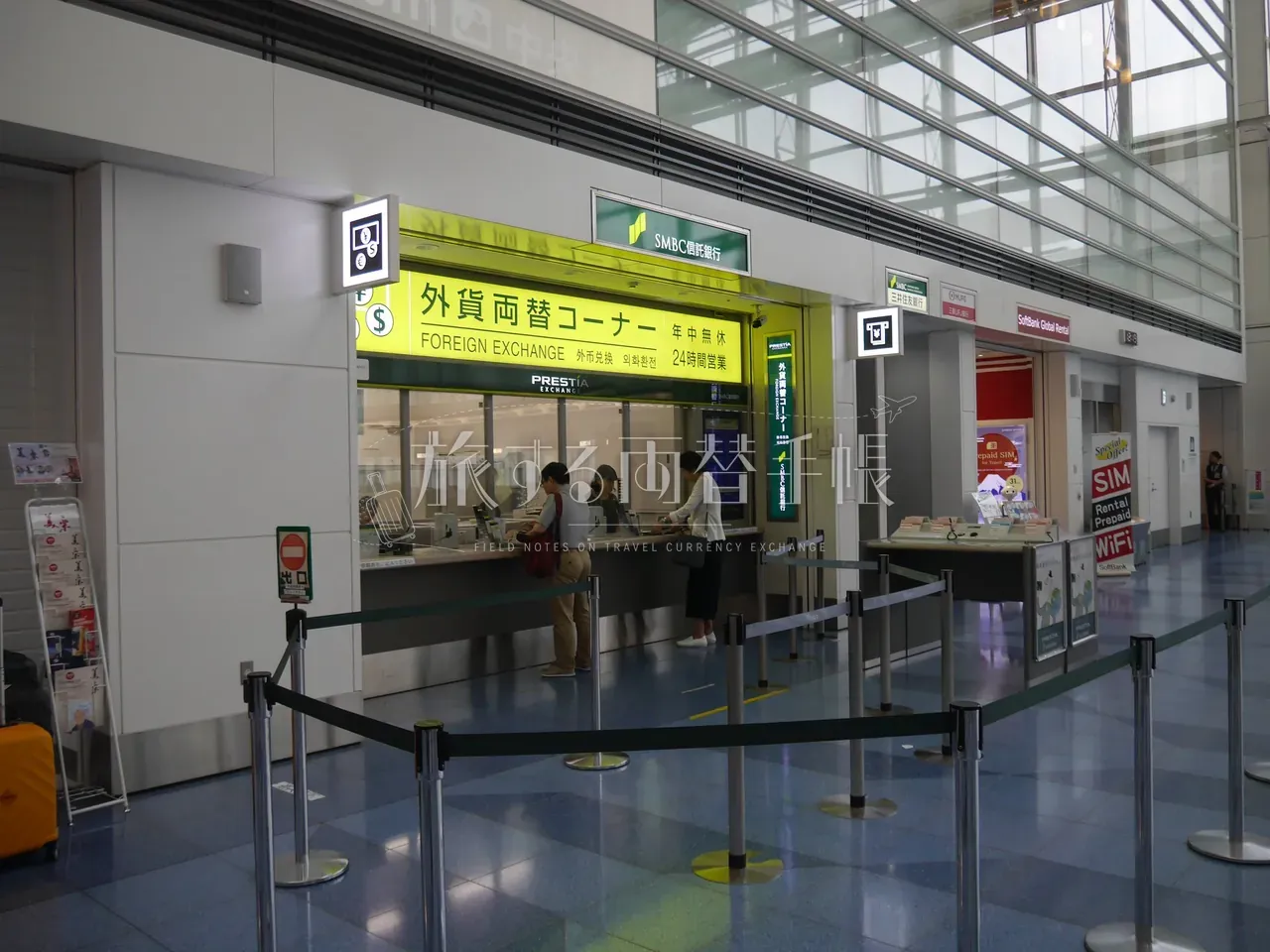羽田空港 SMBC 信託銀行 PRESTIA の外貨両替コーナーで両替手続き中の利用客たち