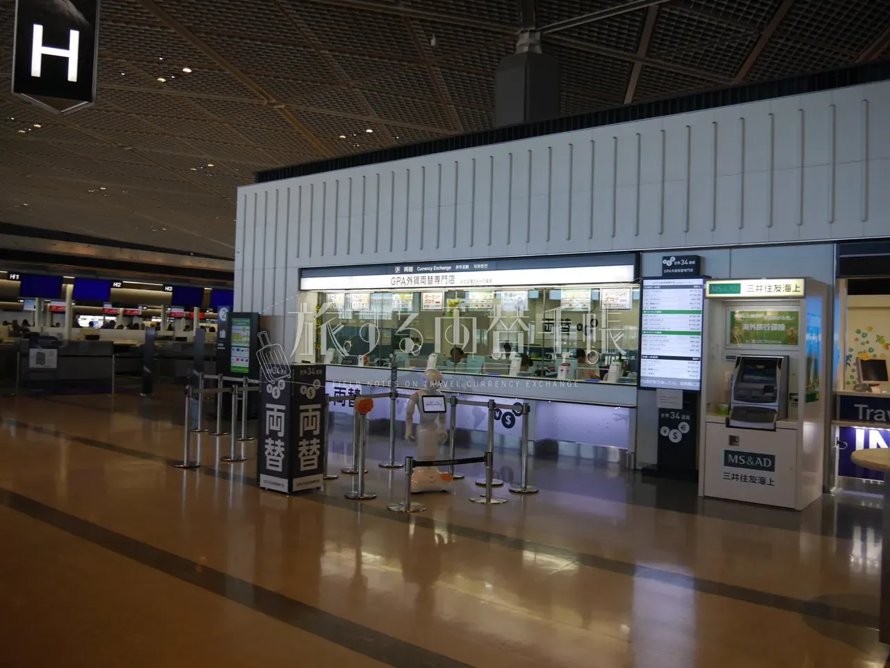成田空港 GPA 外貨両替専門店のカウンター全景と接客中の Pepper ロボット、世界 34 通貨の縦長サイネージ