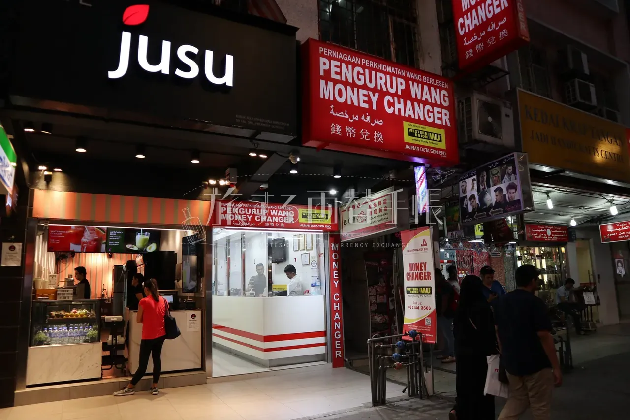 クアラルンプール・ブキッビンタンで夜に営業する両替所 JALINAN DUTA の店頭。多言語の看板が並ぶ