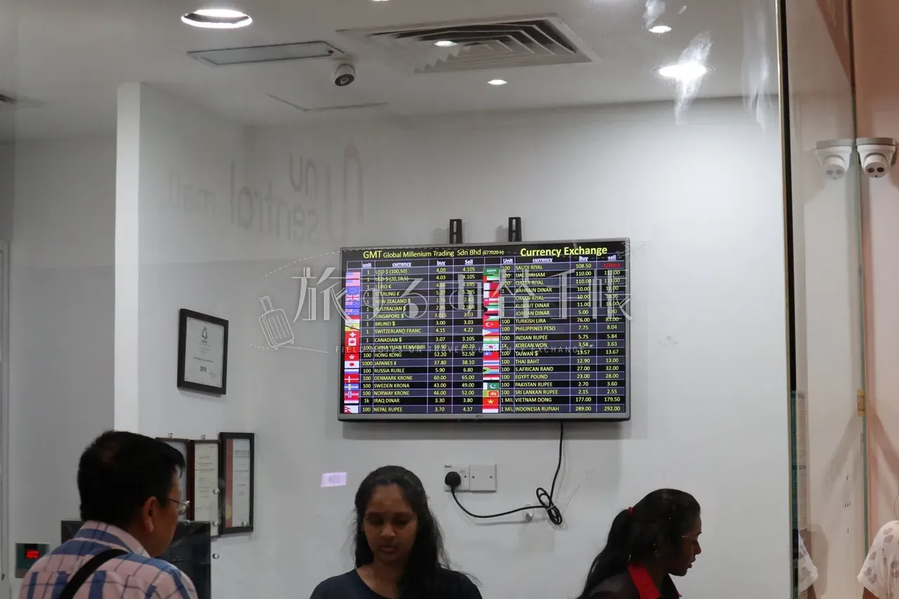 NU Sentral 内 GMT Currency Exchange の電光レート表ボード。USD・EUR・GBP・JPY など 30 通貨超の buy/sell レートが一覧表示