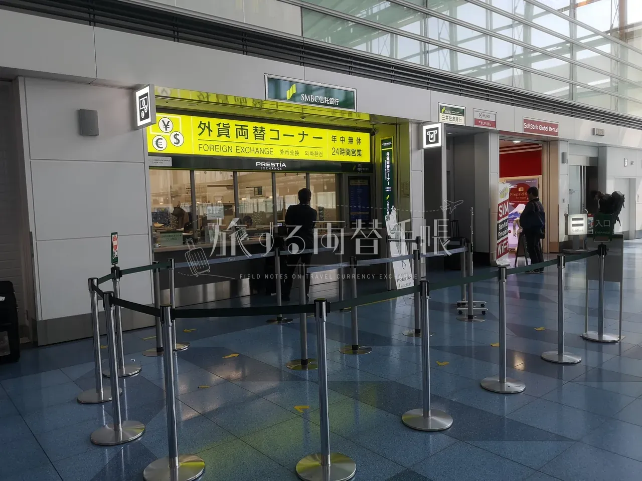 羽田空港 SMBC 信託銀行 PRESTIA の外貨両替コーナー。24 時間営業の窓口と整列スタンション
