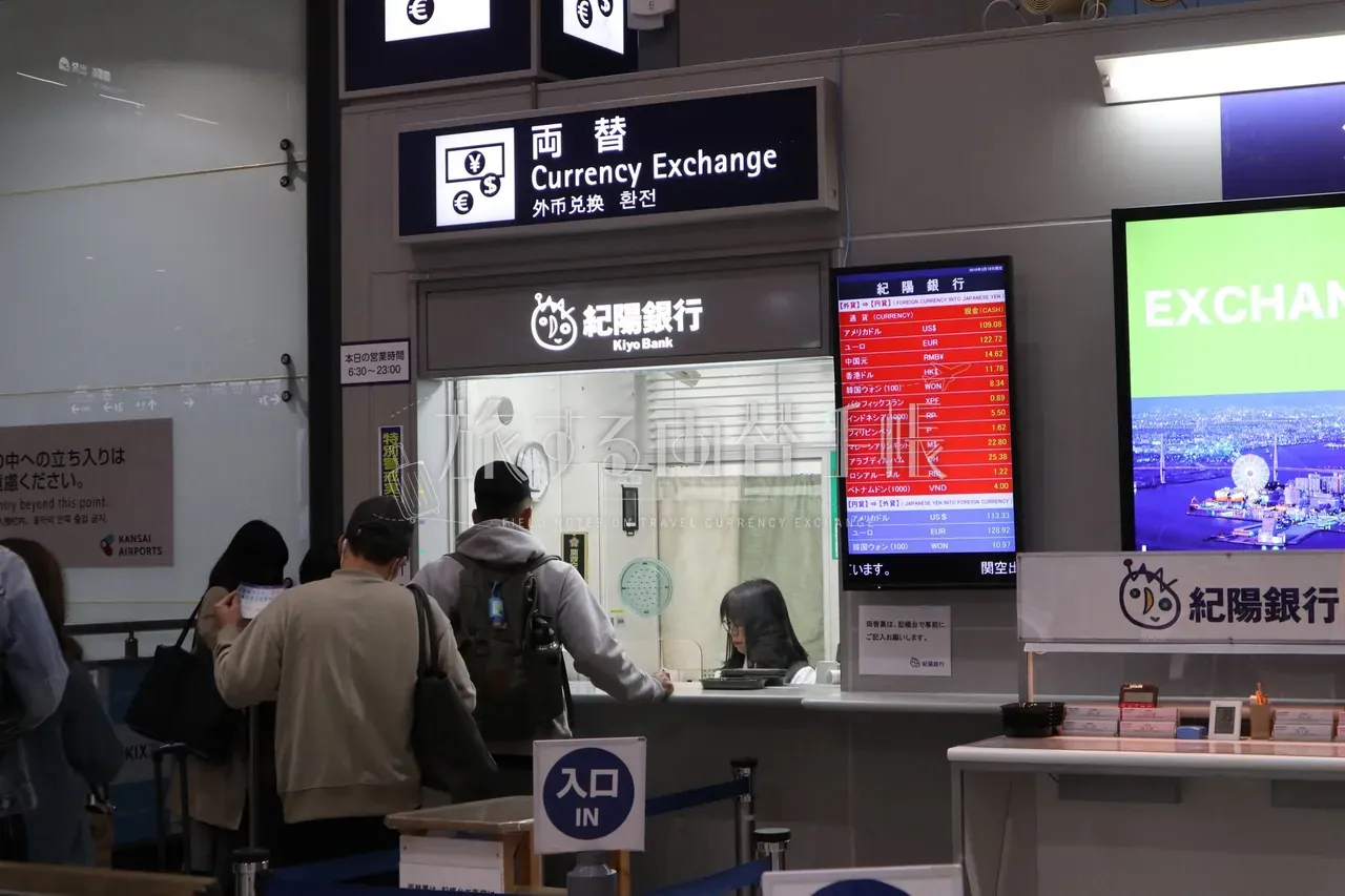 関西国際空港の紀陽銀行の両替カウンターのレートボードと並ぶ旅行者の列