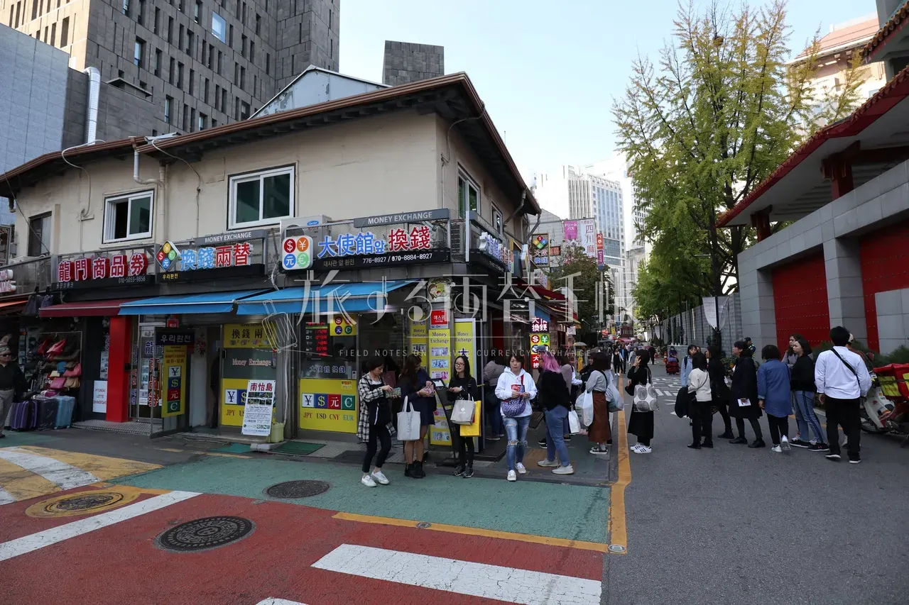 ソウル明洞の角地に並ぶ「大使館換銭」など黄色い両替所の看板が連なる十字路