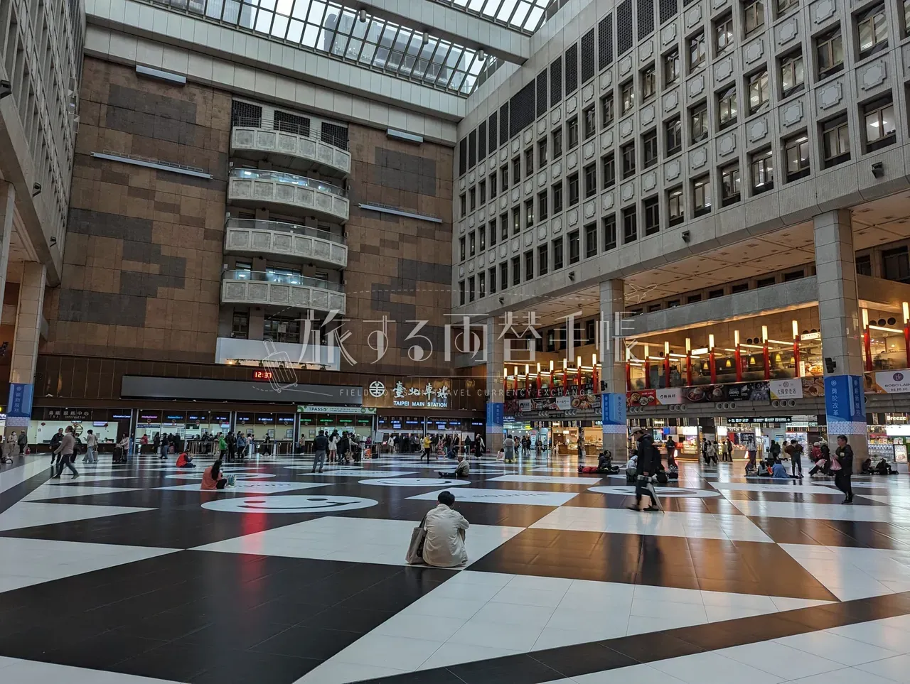 台北車站メインホール。市松模様のタイル床と吹き抜けの大空間に旅客が散らばる