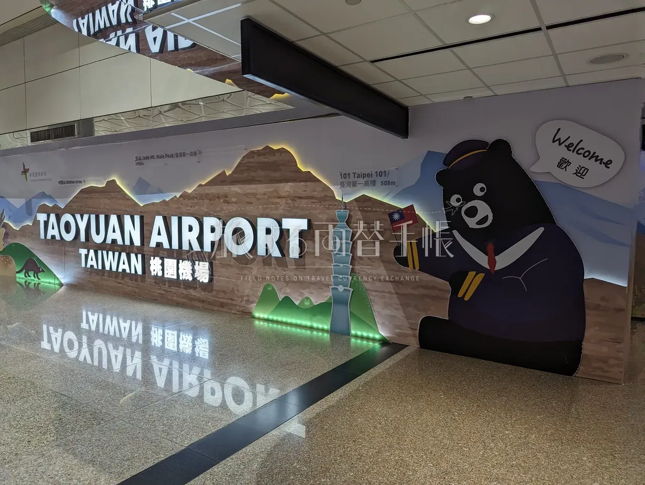 桃園空港ターミナルのウェルカム壁画と台湾黒熊キャラクター。TAOYUAN AIRPORT の文字