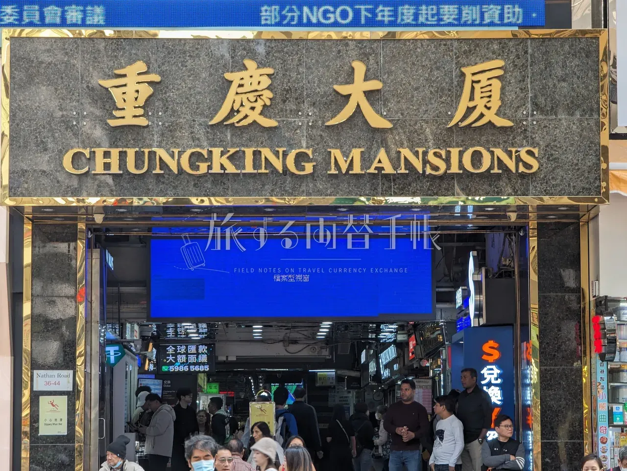 尖沙咀ネイザンロード沿いの重慶大廈 CHUNGKING MANSIONS 正面玄関を見上げた構図、両替店サインが並ぶ