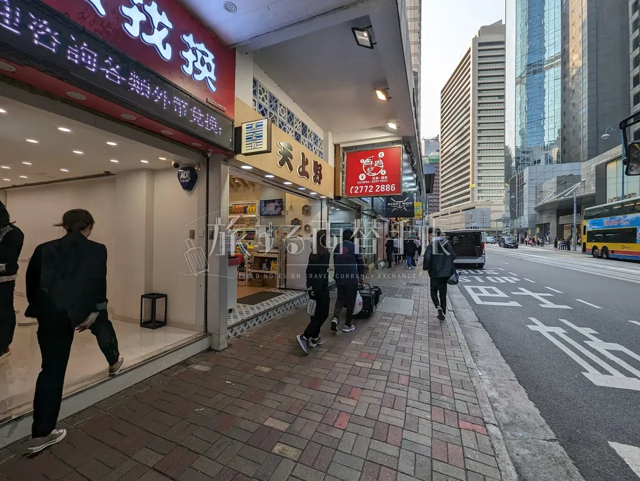 香港の街角に連なる外貨両替を扱う店舗群と歩道を歩く通行人