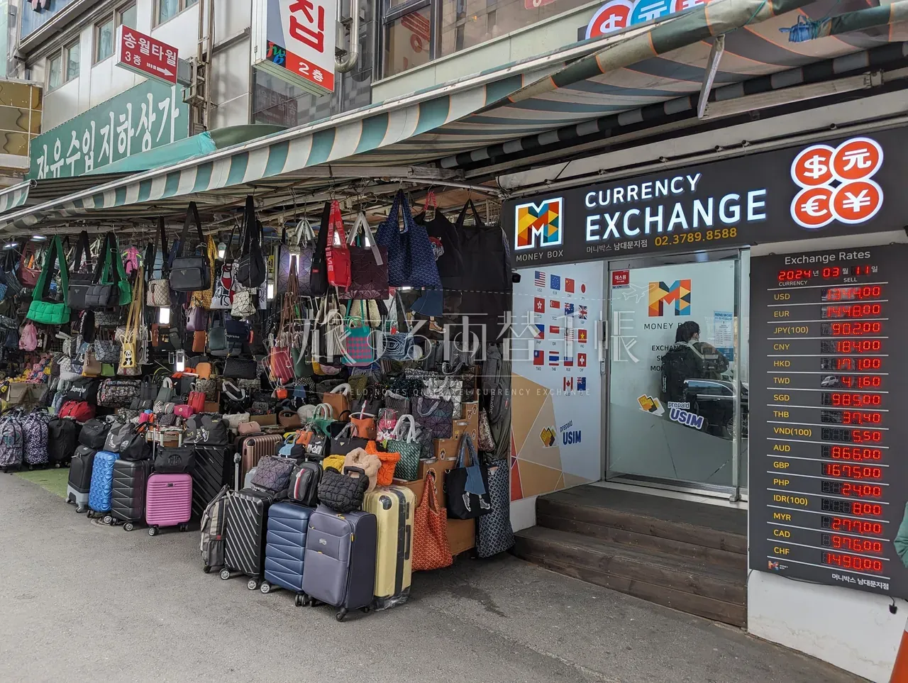 韓国の鞄露店の隣に立つ「MoneyBox CURRENCY EXCHANGE」店舗とレート電光ボード