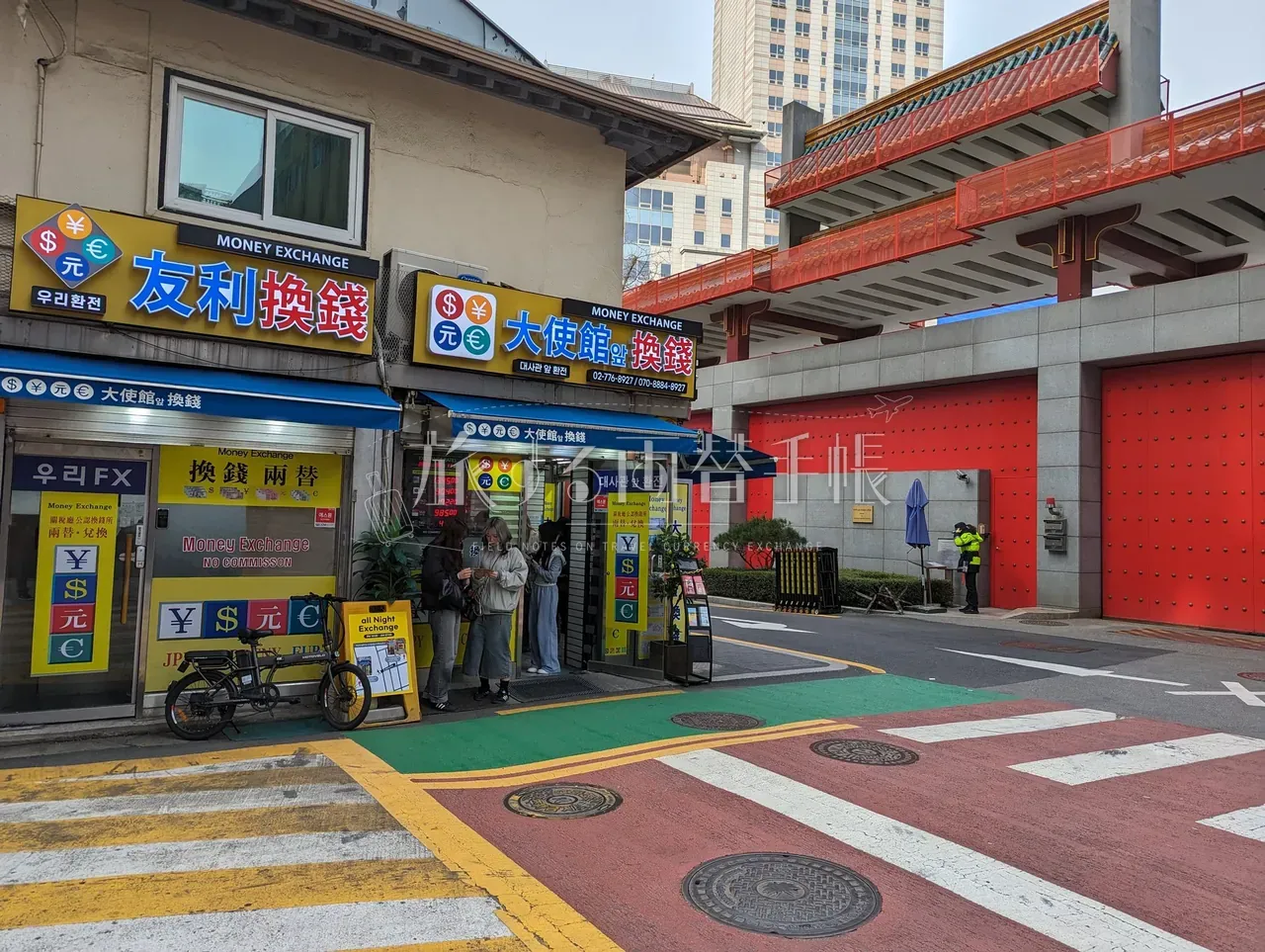 明洞の路地角に並ぶ「友利換銭」「大使館換銭」2軒の店頭で両替手続き中の客