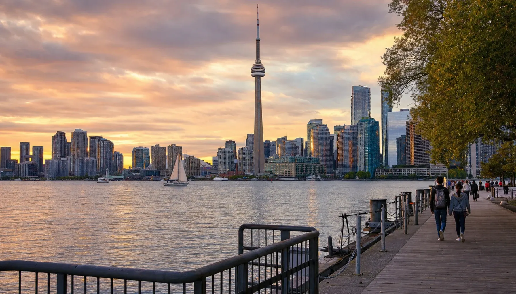 トロントの黄金時間スカイライン。Toronto Islands から望む CN タワーと downtown ビル群が湖面（オンタリオ湖）に映り込む夕景。